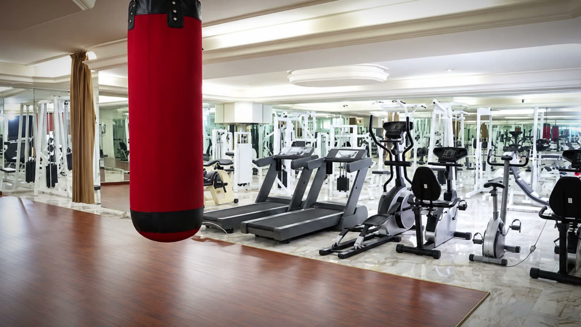 The Viccini Club gym floor: treadmills, bikes and a red punch bag in a bright mirrored room